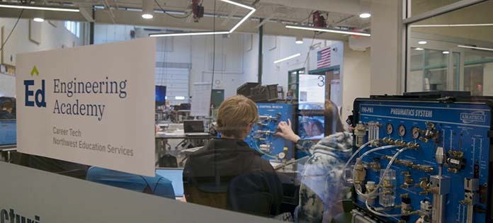 Image of Engineering Academy Students through glass, with the Engineering Academy Logo